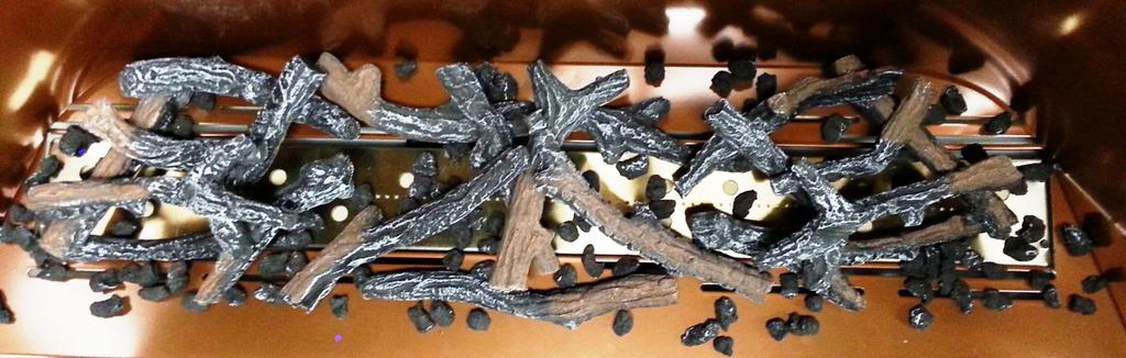 8. Spread Coals in the open areas loosely and in one single layer on top of the burner in the middle open area between the two twig assemblies and also a few pieces on other areas of the burner under