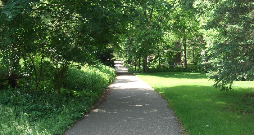The asphalt trail separates the park space from residential property, though some of the residential lots could easily be confused as