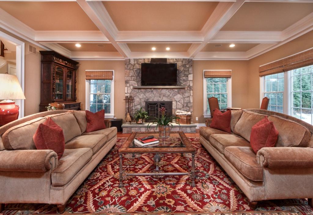An airy Living Room on the left boasts custom finishes, a bay window, ceiling sound system, and an elegant fireplace around which family and guests can gather, which conveniently opens to the Formal