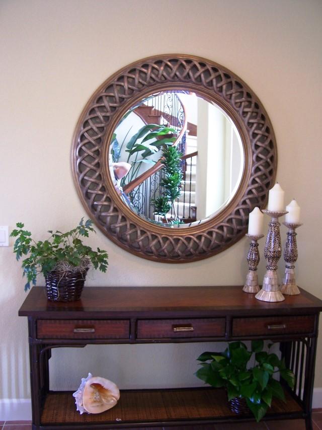 Entryways that Wow Transition: Plant life used as an accessory helps to transition visitors while a large round mirror visually expands the space.