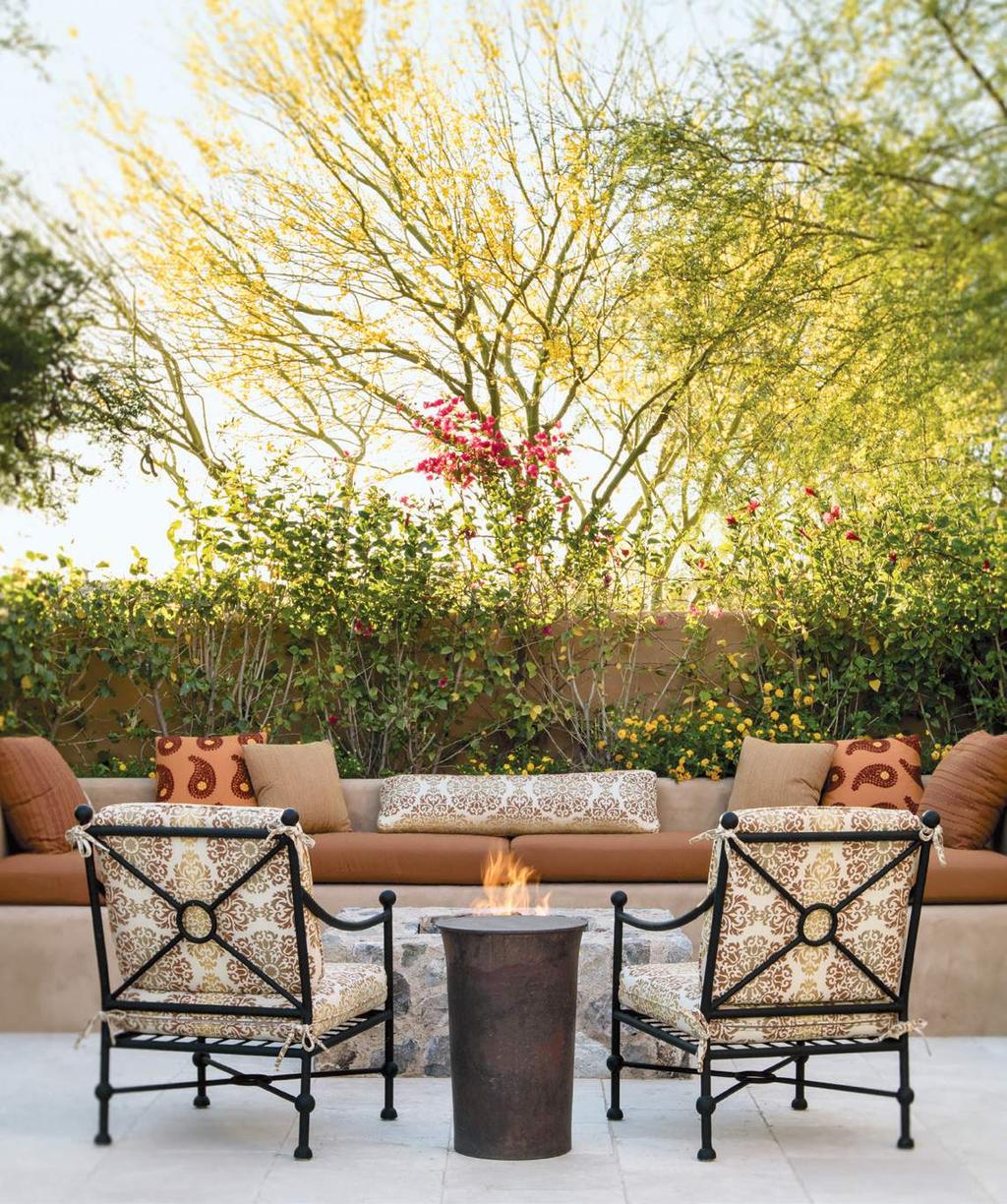 In the rear of the house, chairs by Murray s Iron Works flank a table from Inside/Out to fashion a cozy seating area in front of the fire pit.