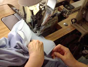 As the trailing edge of the collar nears the machine, the operator folds the placket over the collar and touches the knee switch.