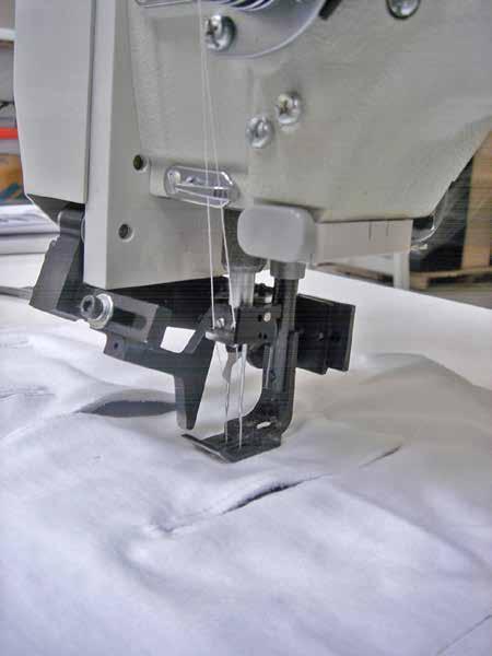 This differential in sew length versus cut length may be changed as desired. The operator places garment panel and pocketing material under presser foot, presses sewing treadle to begin sew cycle.