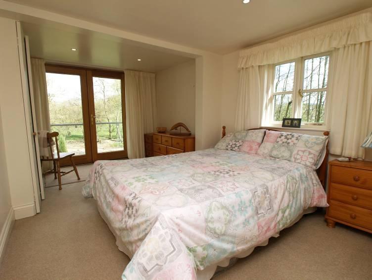 With fully glazed double doors to small balcony with glass panels and metal handrails over-looking the river to farmland, further window to front overlooking farmland, radiator, fitted wardrobe with