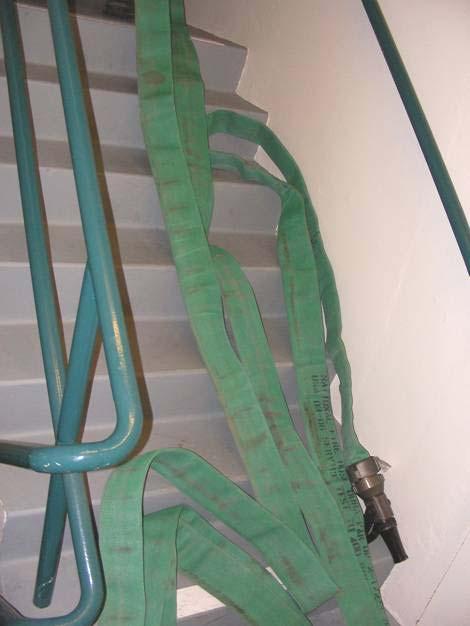 Places hose pack on stairwell, 3-4 steps up from landing with the shutoff and tip facing the outside of the