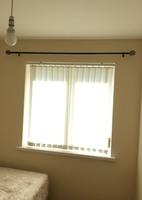 White vertical blinds and a black metal curtain pole.