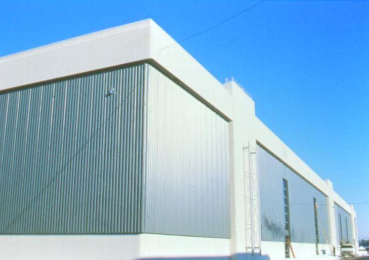 Figure 3: Photo of one wall of the Canadair complex in Montreal with grey solar collector panels and white canopy and vertical dividers With proper design, solar air heating can be incorporated into