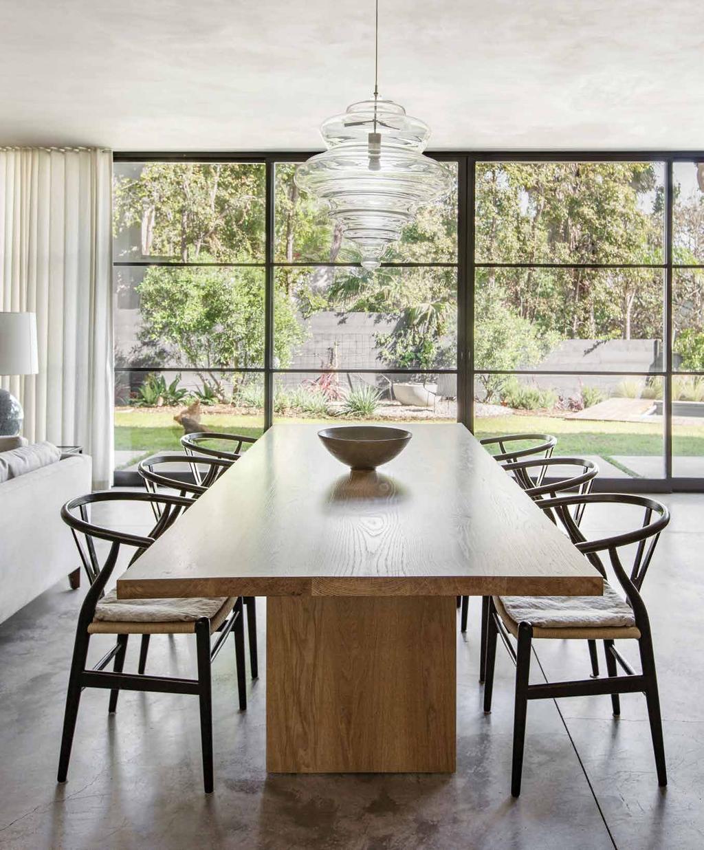 A handblown glass Lasvit pendant from The Line in New York hangs above a custom white-oak table in the dining area. A wall of Torrance Steel Window Co.