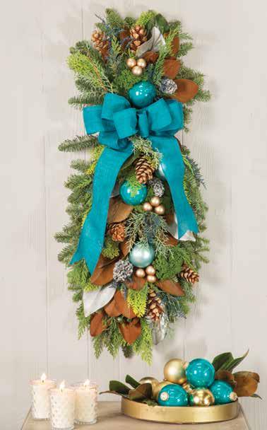 Green and gold magnolia, pinecones, cedar and assorted evergreens provide a luxurious base for the rich ensemble of colored ornaments, plum millet grasses, dried caspia.