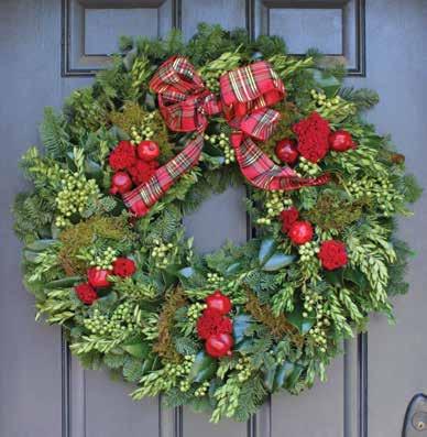 A A B HEART OF THE HOLIDAYS DESIGNER RED- A copper and green fresh magnolia wreath combines with red flowers, pinecones, magnolia pods and red