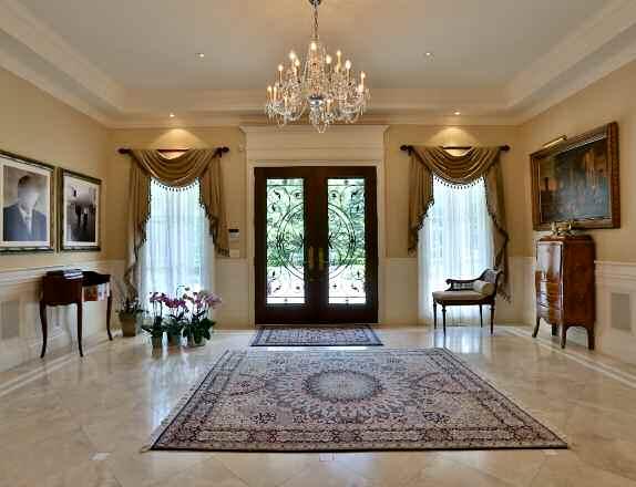 Main Level Foyer The Foyer features a pair of solid wood French entry doors with wrought iron detail, limestone flooring, wainscoting,