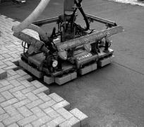 Figure 2 shows a cube of pavers opened and ready for installation by mechanical equipment. When grasped by the clamp, the pavers remain together in the layer.