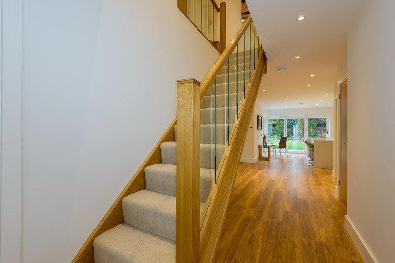 Frosted glass double glazed side screens. Attractive wood effect flooring with underfloor heating. Recessed ceiling lighting. Stairs to first floor with contemporary oak and glass balustrade.