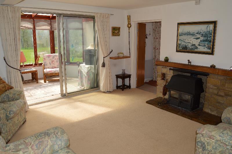 Main Sitting Room measuring approximately overall 14 6 x 16 0 maximum (4.42 x 4.88m) with exposed stone fireplace, timber mantelshelf, stone hearth and wood burning stove inset.