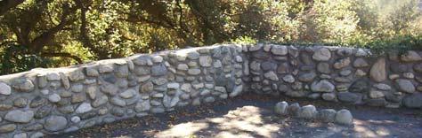 A low arroyo stone garden wall in combination with wrought iron panels painted forest green or black d.