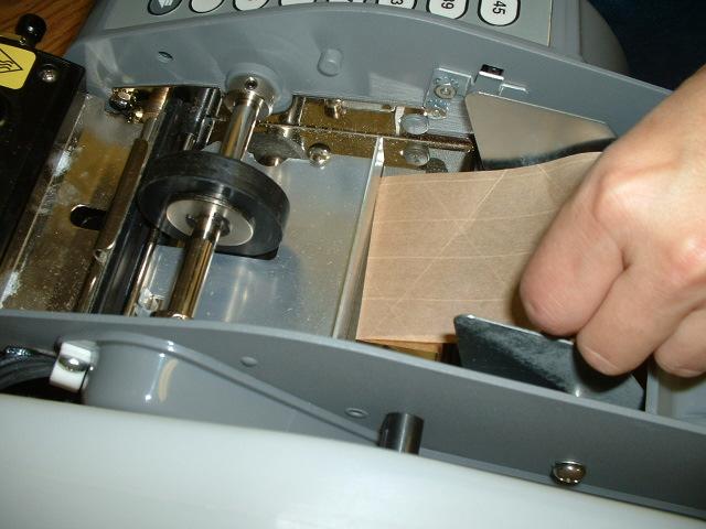 Close the rear cover and open the front cover and proceed to feed the tape under the tape guide. When the tape can go no further, you have properly loaded the tape.