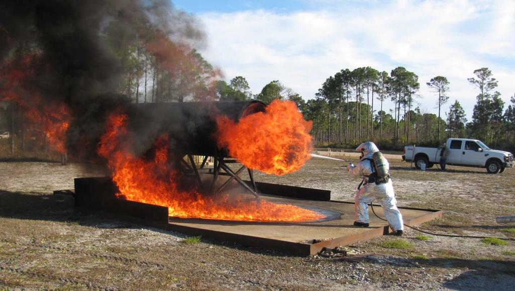 Figure 7. Firefighter Applying Agent during a Rear Engine Fire Test \ Pretest Phase Determine and record extinguisher full weight.