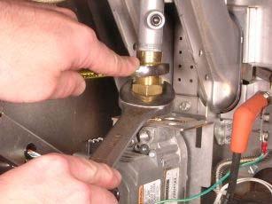e. Using a 1 1/16 wrench and a 7/8 wrench, loosen the brass fitting on the top of the gas valve and disconnect the gas valve from the