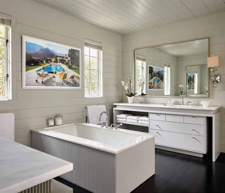 The master bedroom includes an en-suite bathroom, which boasts an oversize soaking tub and his-and-hers vanities while artwork by Slim Aarons purchased from One Kings Lane adds a pop of color and