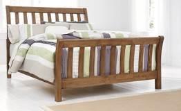 Mindi veneers and hardwood solids in a light brown finish Sleigh shaped bed features wide open slat design Cases have block posts