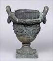 Lot #295: NEOCLASSICAL BRONZE TWO- HANDLED URN Relief cast with putti, goats, and grape clusters, flanked by loop handles supporting husk swags, 21 x 17 in. (over handles).