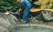 Let the liner drop into the pond, making sure it extends evenly, well beyond the perimeter. Minimize the number of small folds by pulling or tucking them into large folds.
