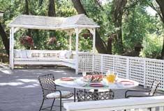 A Construction Common deck is enhanced by a shady set of twin trellises with a sloping design. Built-in benches and redwood fence complete the attractive setting.