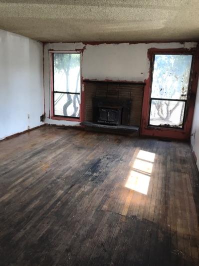 1. Living Room Living Room Walls and ceilings appear in poor condition overall. Flooring is wood.