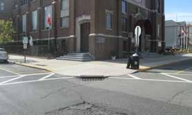 Stormwater flows from downspouts directly onto adjacent sidewalks and streets, where it then travels