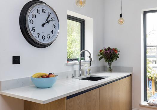 Sleek handle-less doors keep the kitchen clean and modern, creating a wondrous feel of open space, which is enhanced further by gleaming white quartz worktops bouncing natural sunlight throughout the