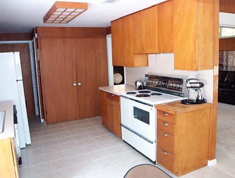 The door on the left opens to a pantry, while doors above the fridge and below the oven provide storage for lesser-used items. A stereo speaker is concealed just above the oven.