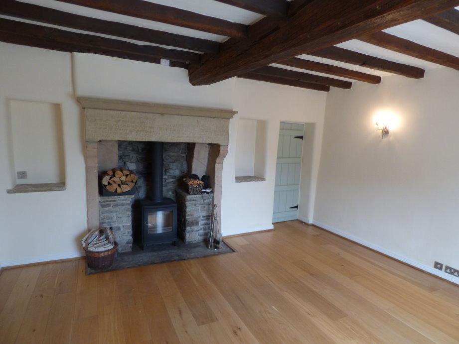 Three double wall light fitments and double panelled central heating radiator, main feature of the room being a stone & flagstone-built fireplace with slate hearth with decorative tiled surround