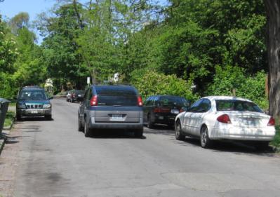 A 28 foot street with parking on both sides provides clearance for one vehicle in the drive lane, requiring queuing when there are two vehicles approaching one another.