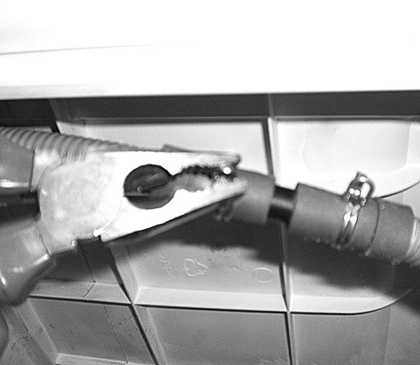 A grey hose connects to the bridge at the left hand side of the machine. Using pliers, remove the pipe retaining clip from the bridge. 6.
