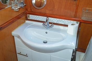 Vanity unit with wash basin, chrome mixer taps and a cupboard beneath.