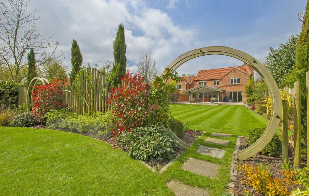Extensive central lawn separated from a less formal garden by shrubbery planting/circular pergolas.