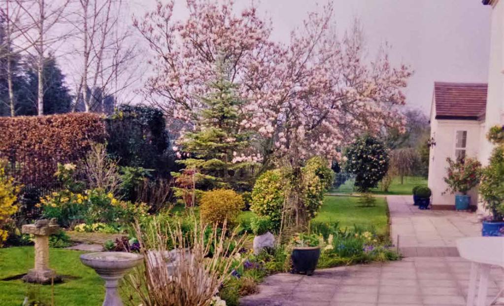 There are formal gardens to the side of the house planted with a variety of mature shrubs and trees.