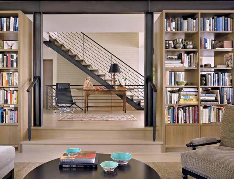 Above: The stairway landing outside the library features a Herman Miller Eames chair and an old wooden farm table displaying a sculpture made by the homeowner s aunt and a lamp with a wallpaper