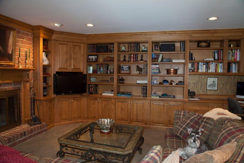 Den has custom made bookshelves and cabinets that provide a space for a TV and a built in desk