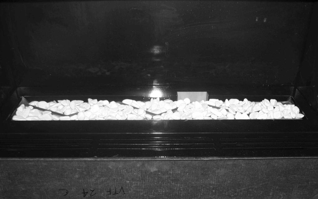 5.7 REMOVAL & RE-FITTING THE FUEL-BED PEBBLES Remove the glass panel as shown on pages 53-54 before attempting to remove or replace the logs. 5.7.1 Fit the pebbles to the burner tray as shown below in figure 24, do not fill the flame ports in the burner with pebbles.