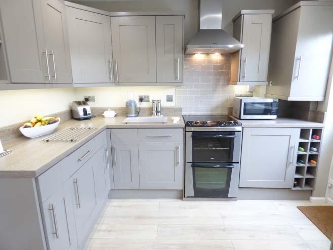 matching splashback and inset 1 1/2 bowl stainless steel single drainer sink unit, space for an electric oven with tiled splashback and stainless steel effect hood over, cupboard housing the