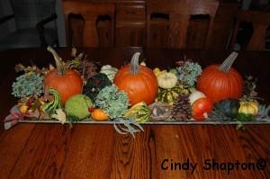 Using a 3- tiered container or stacked cake plates lay different gourds, mini pumpkins and winter squash on the tiers, add colorful leaves, bunches of fresh herbs like rosemary, thyme, lamb s ear or