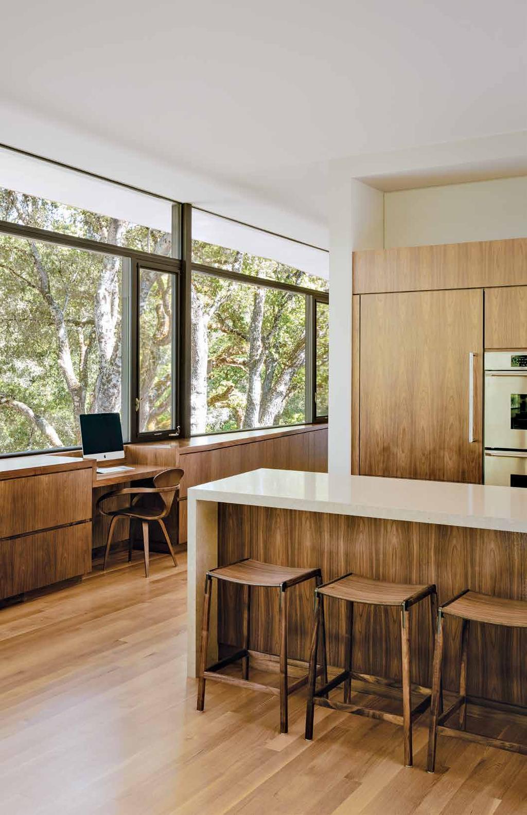 A set of custom walnut-andaluminum barstools by Fyrn complements the custom kitchen cabinetry designed by Sagan Piechota Architecture and
