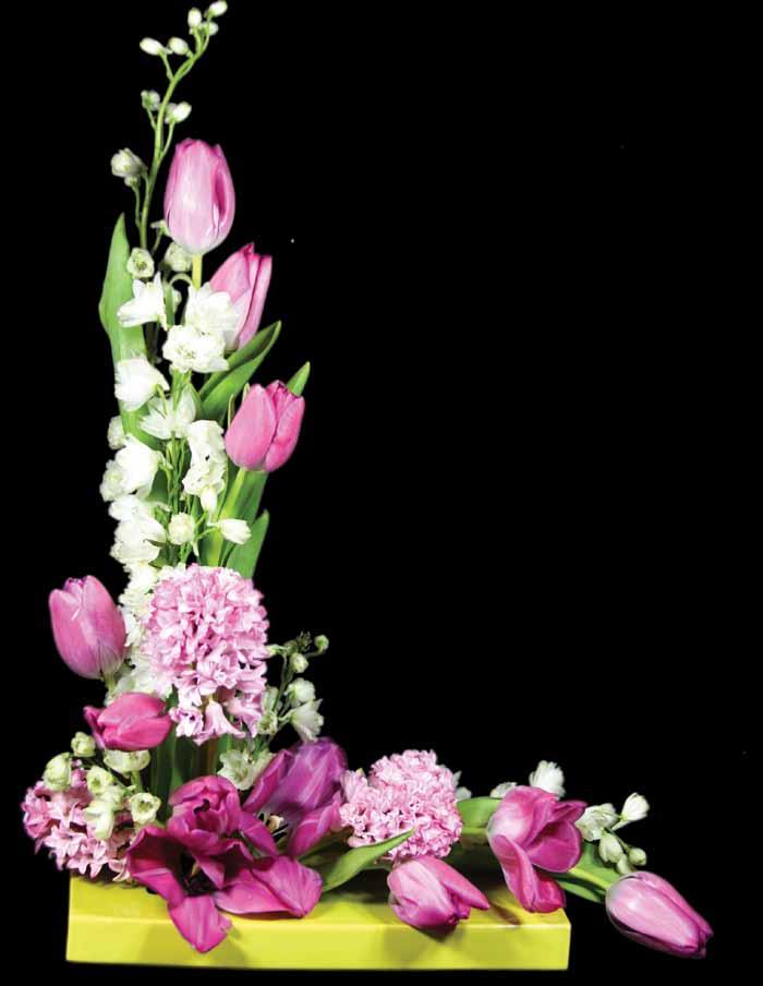 L- SHAPE Into a rectangular vase upright stems of white Larkspur and pink Tulips are used to create the beginning of this L- shaped design.