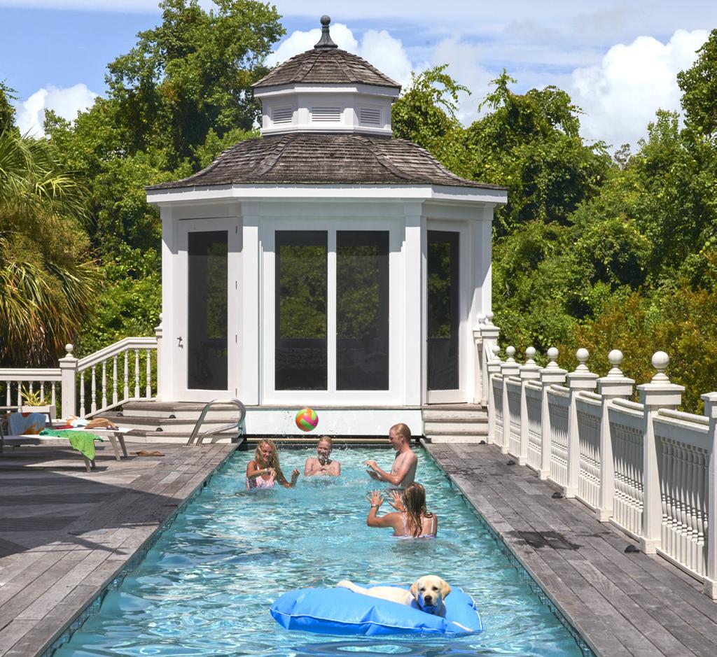ABOVE: Four of the Cochran kids from left, Faith, Hugh, Will, and Olivia take a dip in the home s lap pool along with Archie, the family s dog. Gazebo in Benja - min Moore s Super White.