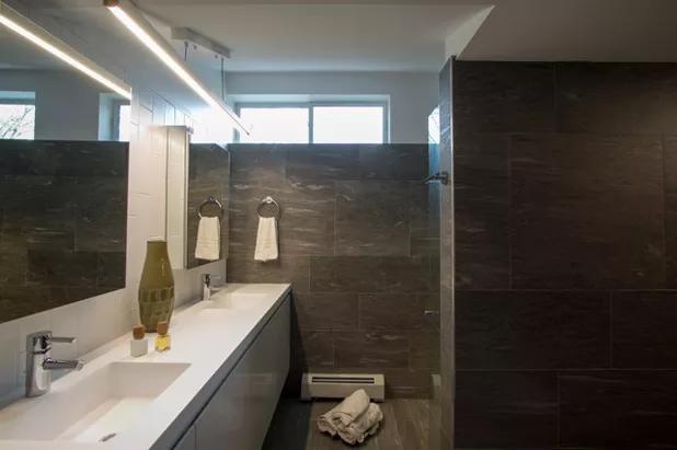 The shower and the vanity area benefit from the light the most, while the toilet is in an alcove behind the wall on the right.