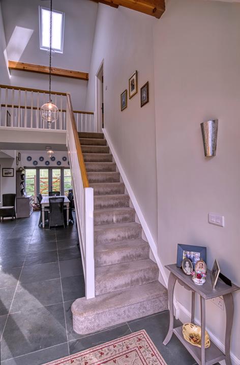 Painted balustrades and a natural wood handrail line the stairs and the suspended landing