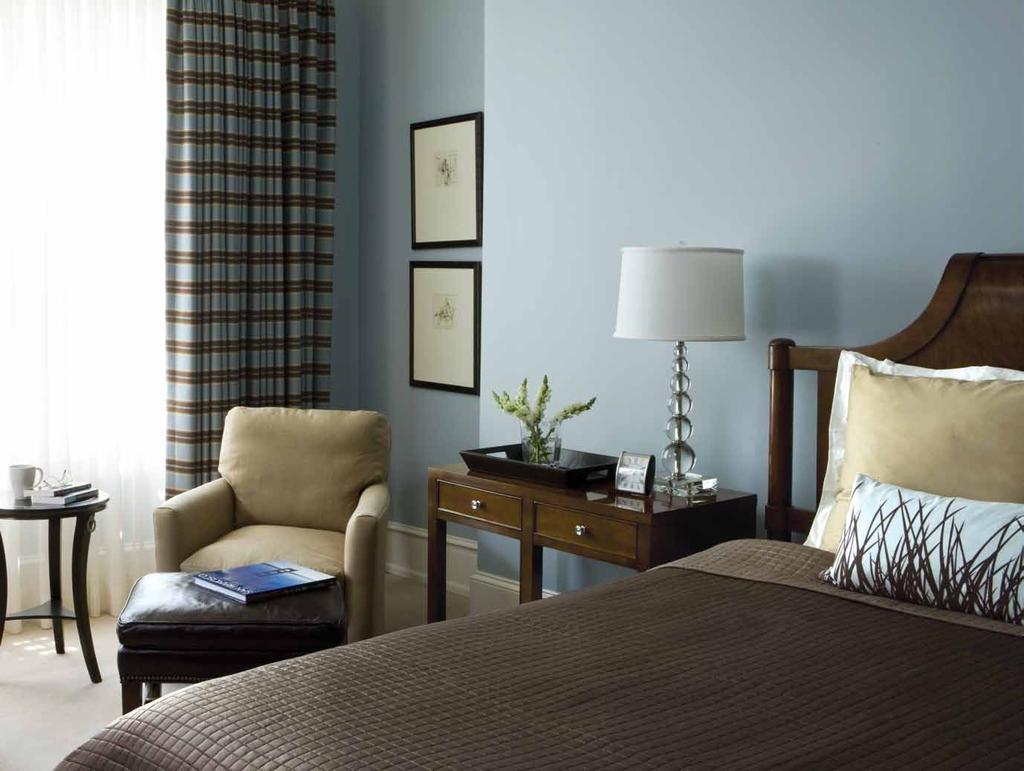 The master bedroom is painted a calming, pale gray-blue; Welch added a conversation zone with club chairs by the windows.