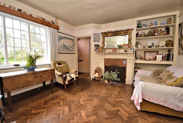 Exposed pine floorboards, open fireplace with tiled hearth and brick surround, built in bookshelving and fitted cupboard, two double radiators and a door opening to the playroom.