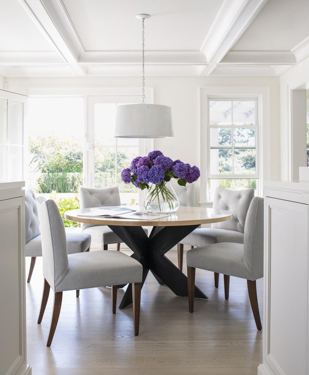 Dining room Tufted chairs by Charles Stewart Company gather around a custom-designed dining room table with a dramatic black X-base.